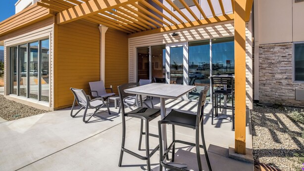 An outdoor patio with a pergola, seating, and a view of the cityscape.