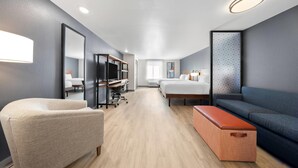 A modern hotel room with a sofa, a chair, a desk, and a bed. - Everhome Suites San Bernardino - Loma Linda (San Bernardino)