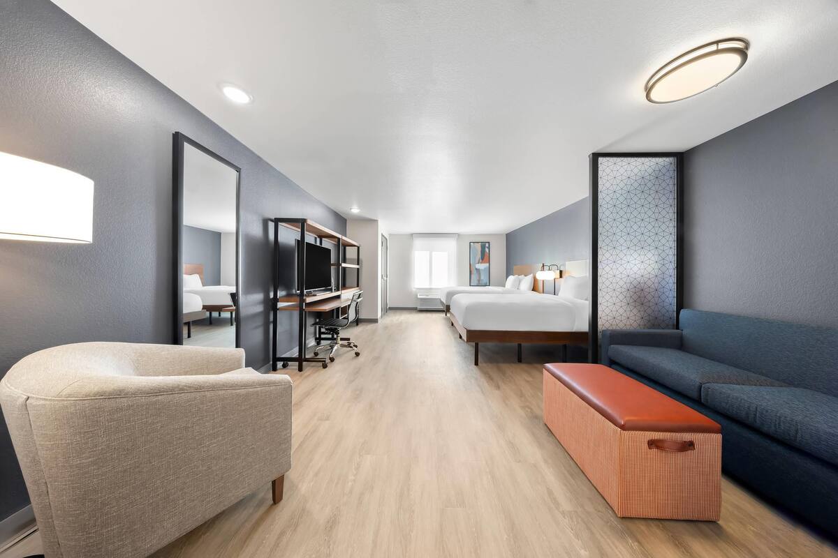 Une chambre d’hôtel moderne équipée d’un canapé, d’un fauteuil, d’un bureau et d’un lit.