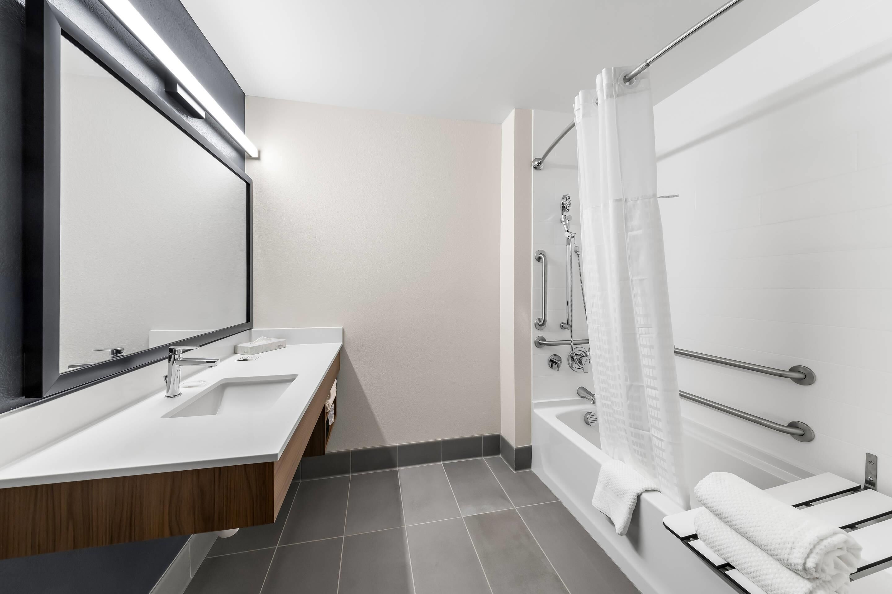 Un baño moderno con lavamanos doble, un espejo grande, ducha con puerta de vidrio y un perchero para toallas.