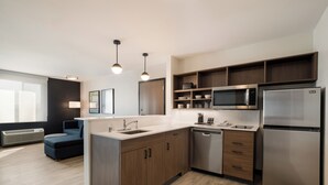 A modern kitchen with wooden cabinets, stainless steel appliances, and pendant lighting. - Everhome Suites San Bernardino - Loma Linda (San Bernardino)