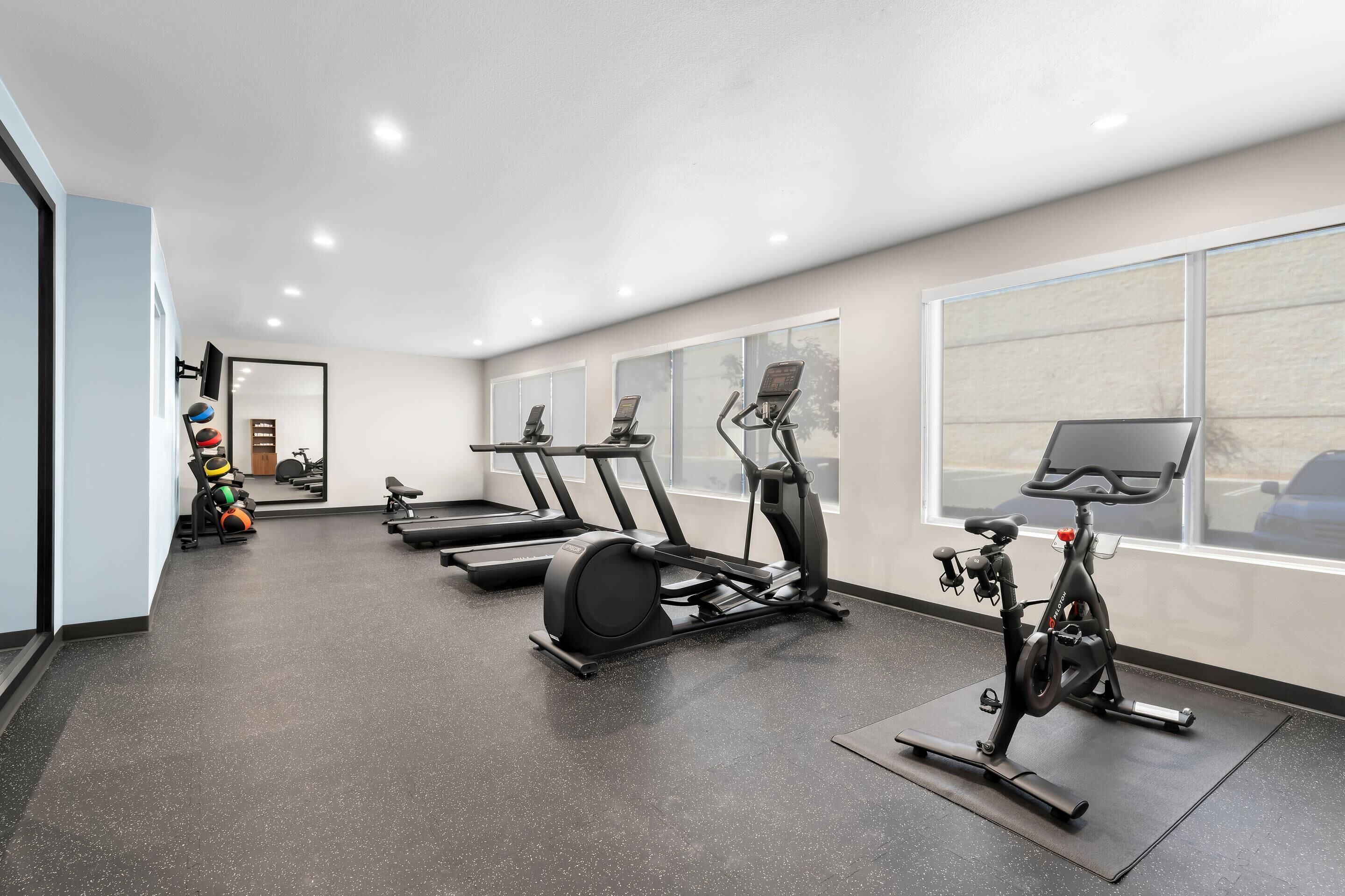 A modern gym with treadmills, an elliptical, and a stationary bike.
