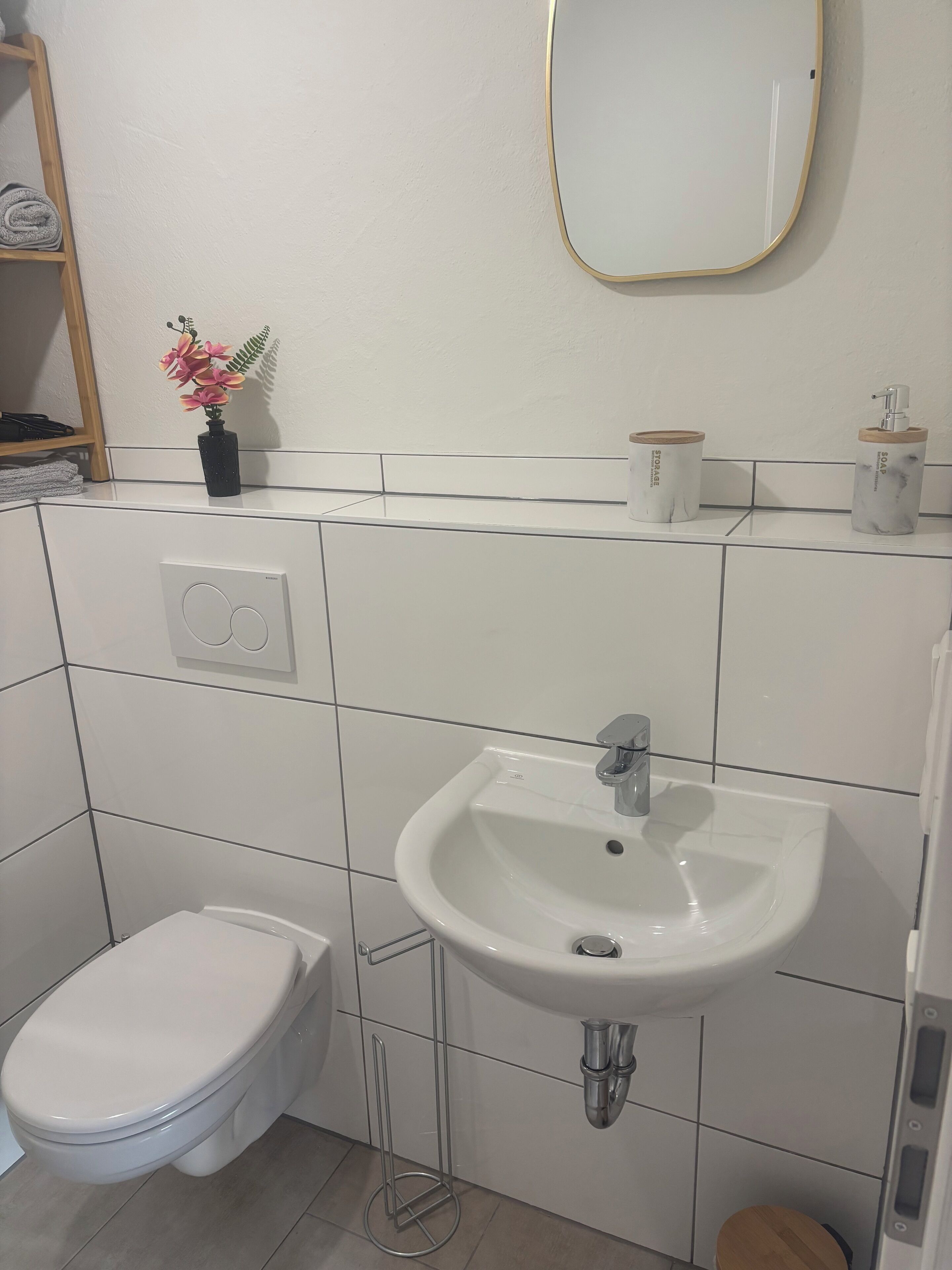 A bathroom with a white sink, toilet, and a mirror above the sink.