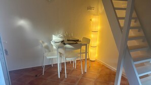 A dining area with a table set for four, a tall floor lamp, and a white staircase. - Cozy apartment directly on the Rhine (Wiesbaden)