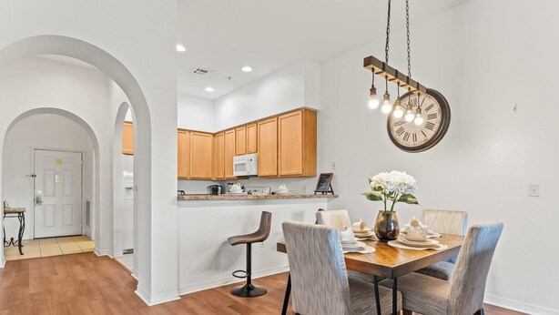 A modern kitchen with wooden cabinets, a microwave, and a dining area with a wooden table and chairs.