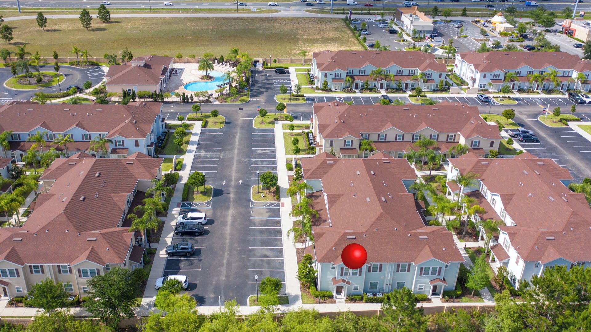 A residential area with multiple two-story houses, a central road, and a swimming pool.