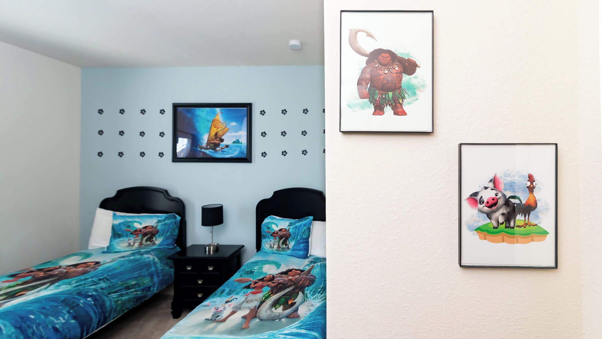 Quarto com duas camas, cada uma com roupa de cama com tema oceânico. Há uma TV fixada na parede acima das camas e duas imagens emolduradas na parede.