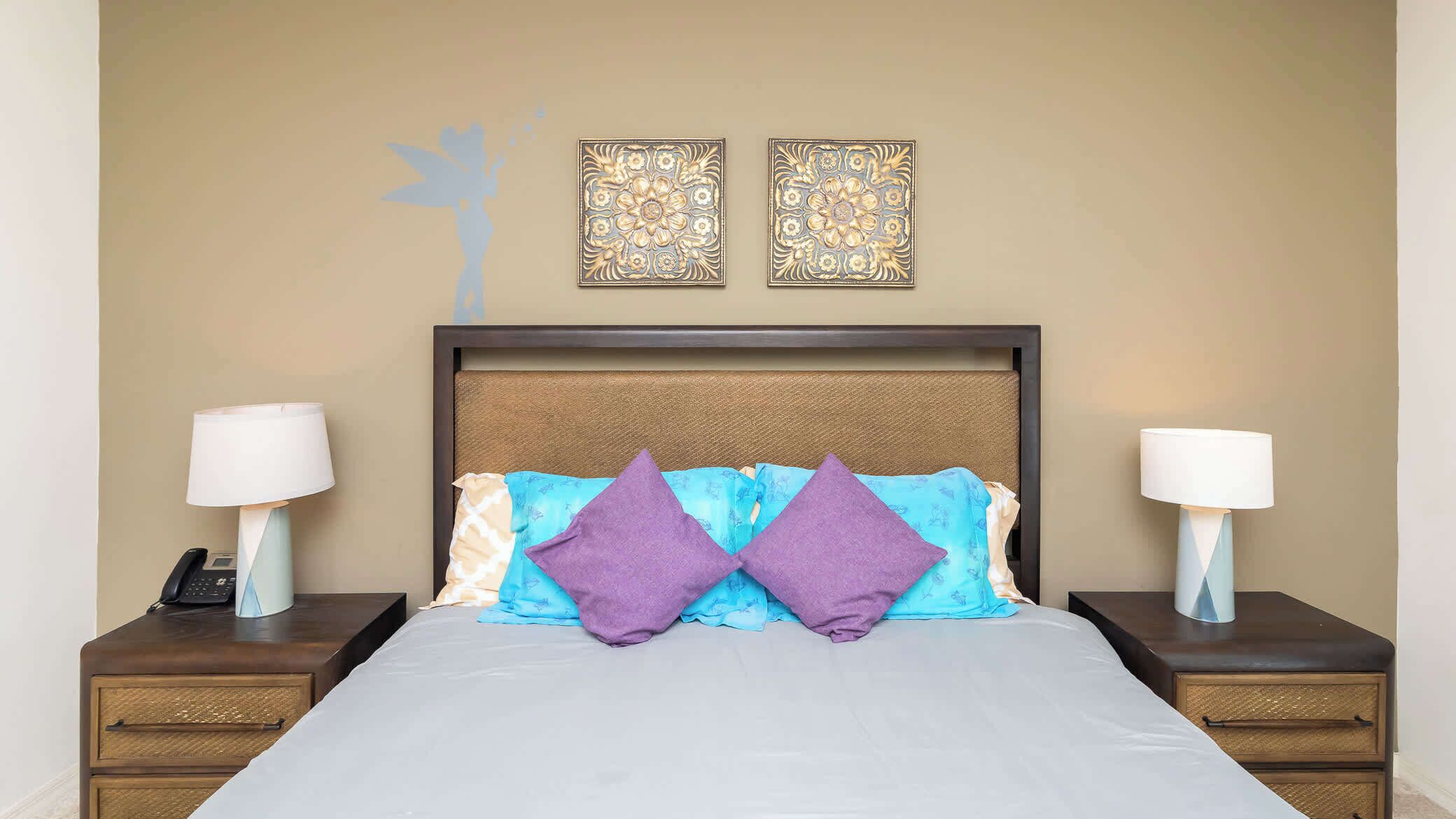 Habitación de hotel con cama, dos mesitas de noche, teléfono y decoración mural.