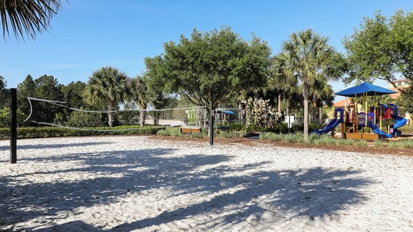 A sandy beach area with a playground featuring slides and climbing structures.