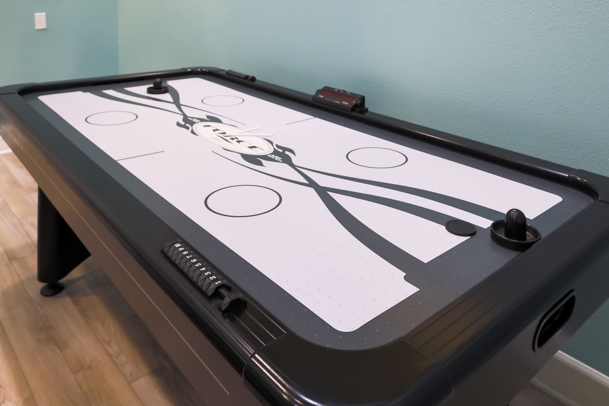 Uma mesa de bilhar com tecido branco e detalhes em preto, incluindo um logotipo e bolsos numerados.