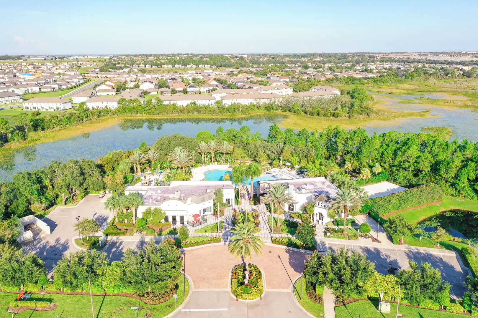 Luchtbeeld van een resort met een zwembad, palmbomen en een parkeerplaats.