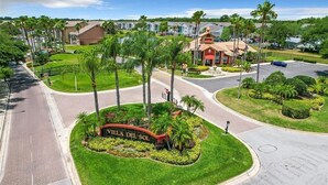 A landscaped area with a sign reading "VILLA DEL SOL" surrounded by palm trees and well-maintained grass. - Adventure's at Villa Del Sol (Kissimmee)