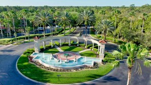 A landscaped area with a central fountain, palm trees, and a sign reading "Emerald Island." - Be Our Guest at Emerald Island (Kissimmee)