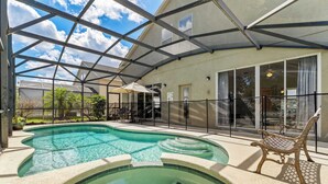A swimming pool with a glass enclosure, a bench, and a covered patio area.