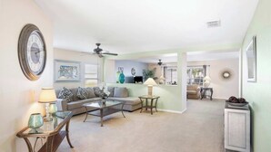 A spacious living room with a sofa, coffee table, and decorative lamps. There is a dining area with a table and chairs in the background. - Magic Oasis Retreat (Davenport)