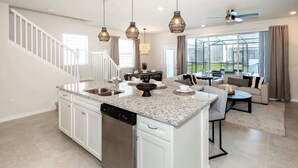A spacious kitchen with granite countertops, a dishwasher, and a dining area with a round table and chairs. - Adventure of a Lifetime! 5 BDR at Windsor Island (Davenport)