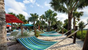 A beachside area with hammocks, palm trees, and a pool with lounge chairs. - Adventure of a Lifetime! 5 BDR at Windsor Island (Davenport)