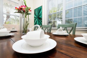 Mesa de comedor dispuesta con vajilla blanca y un florero con flores.