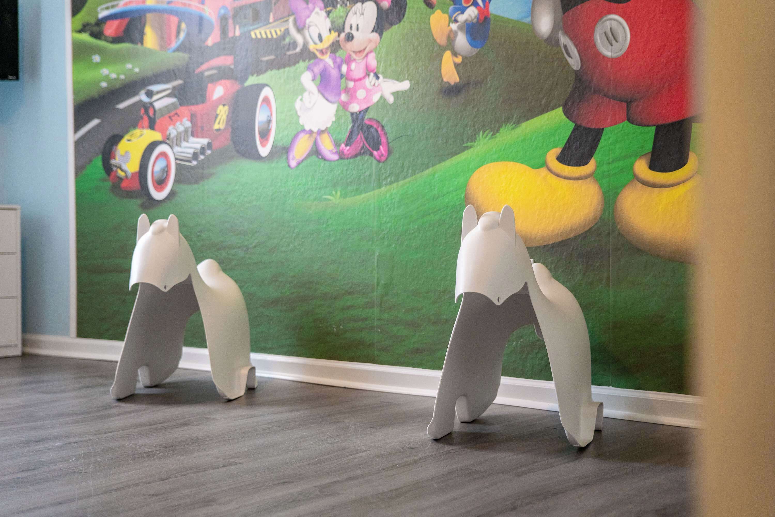 A room with a mural of animated characters and a grey, abstract sculpture in the foreground.