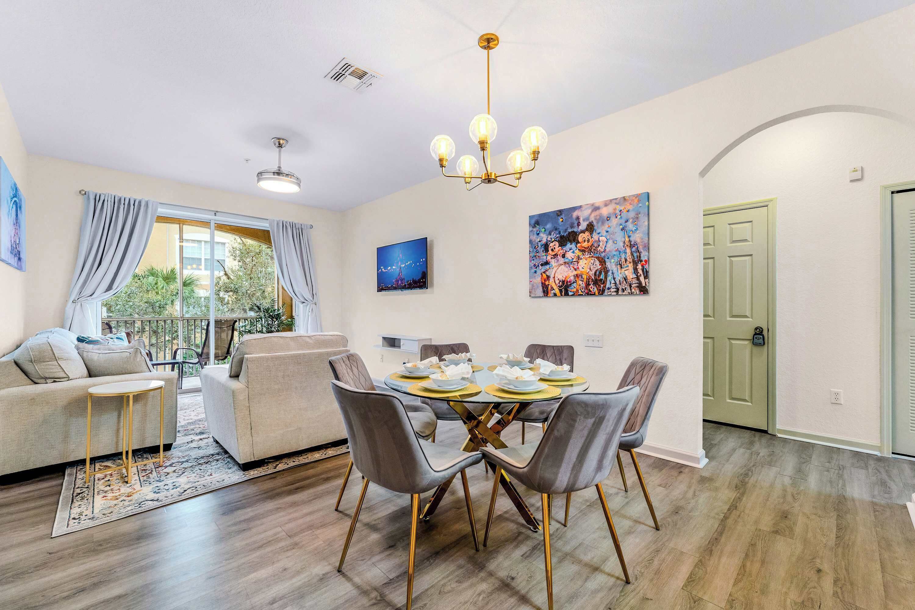 A dining area with a round table, chairs, and a chandelier.