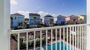 A residential area with colorful houses, a swimming pool, and a white balcony railing.
