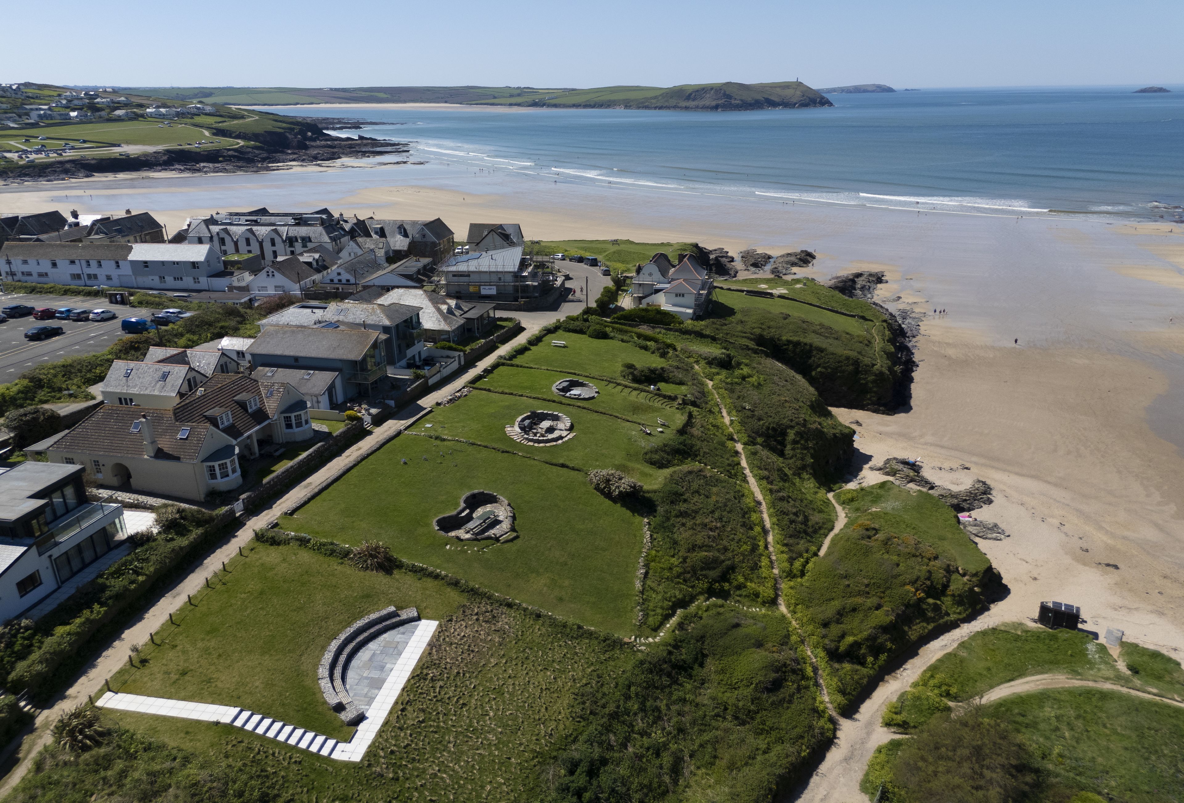 An aerial view of a coastal town with houses, a beach, and a clear sky.