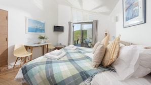 Una habitación de hotel moderna con cama, escritorio, silla y vistas al exterior.