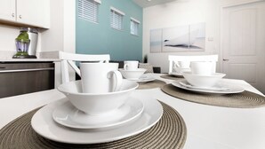 A dining area with white tableware and a kitchen in the background. - Up to Scale With Margaritas (Kissimmee)