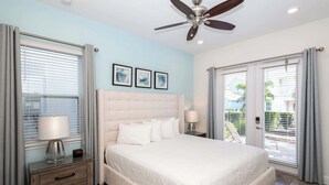 A bedroom with a bed, a nightstand, a lamp, a ceiling fan, and a window with blinds. - Up to Scale With Margaritas (Kissimmee)