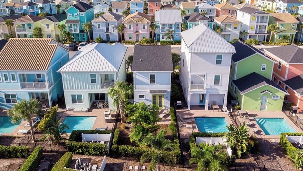 A residential area with colorful houses, a swimming pool, and a small garden area. - Up to Scale With Margaritas (Kissimmee)