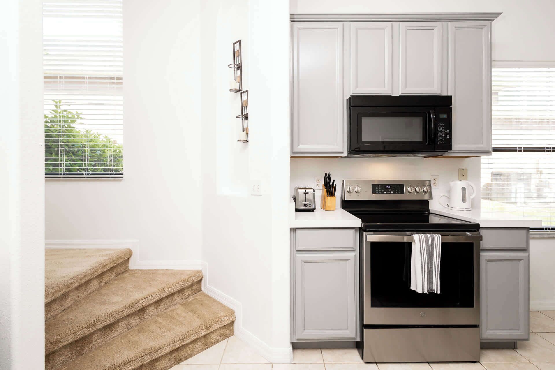 A modern kitchen with white cabinets, a black microwave, a stainless steel oven, and a toaster.