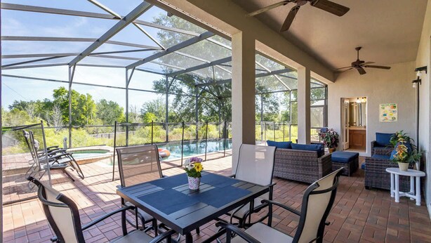 Un patio couvert avec une piscine, des sièges d’extérieur et un ventilateur de plafond.