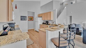 Una cocina moderna con encimeras de granito, armarios de madera y una isla central con taburetes de bar.