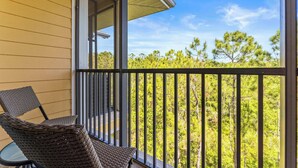 A balcony with wicker furniture and a view of trees. - Slice Of Sunshine At Caribe Cove (Kissimmee)