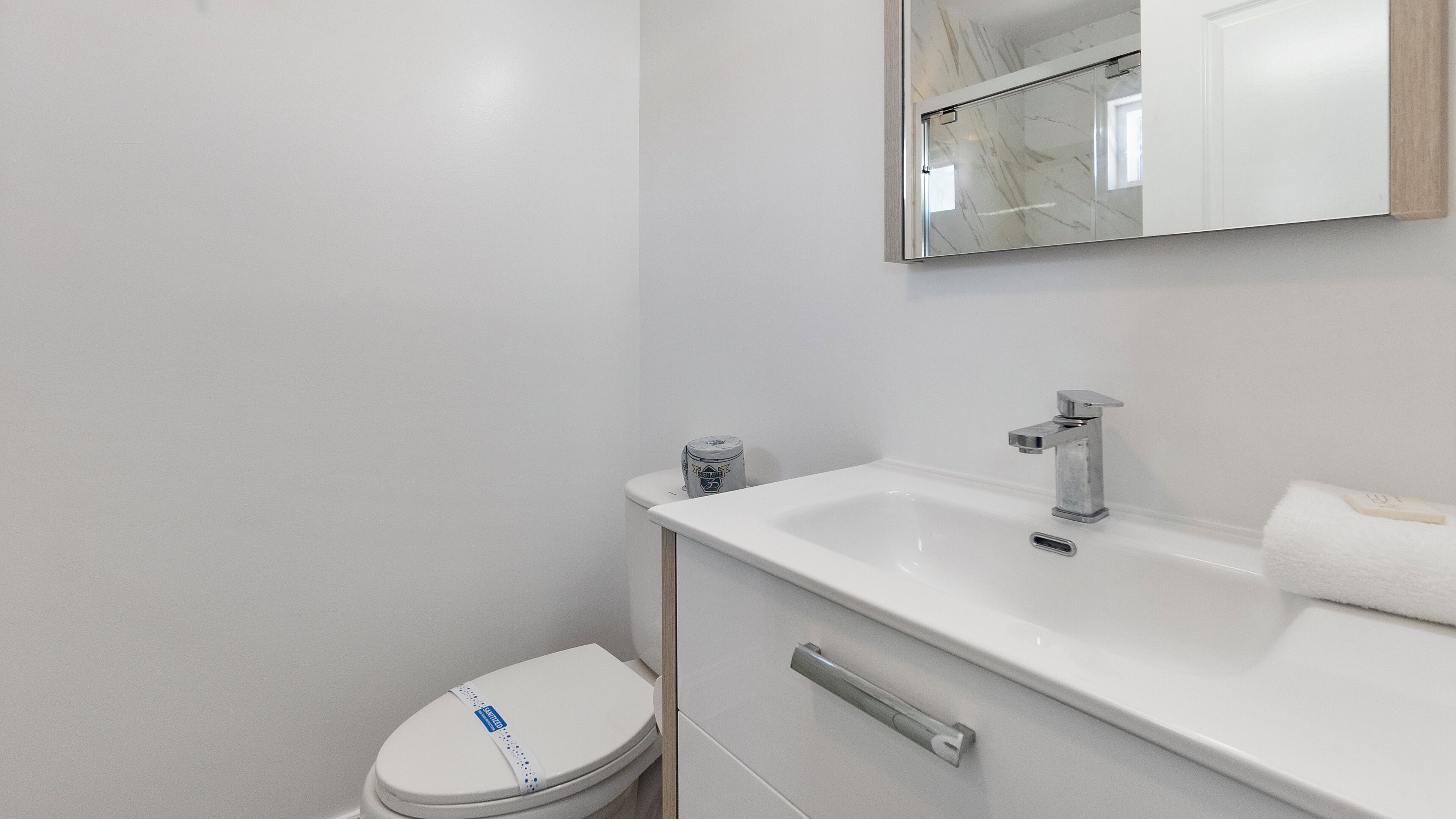 Un baño moderno con inodoro, lavamanos y espejo.