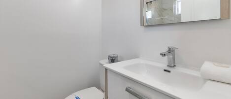A modern bathroom with a toilet, sink, and mirror.