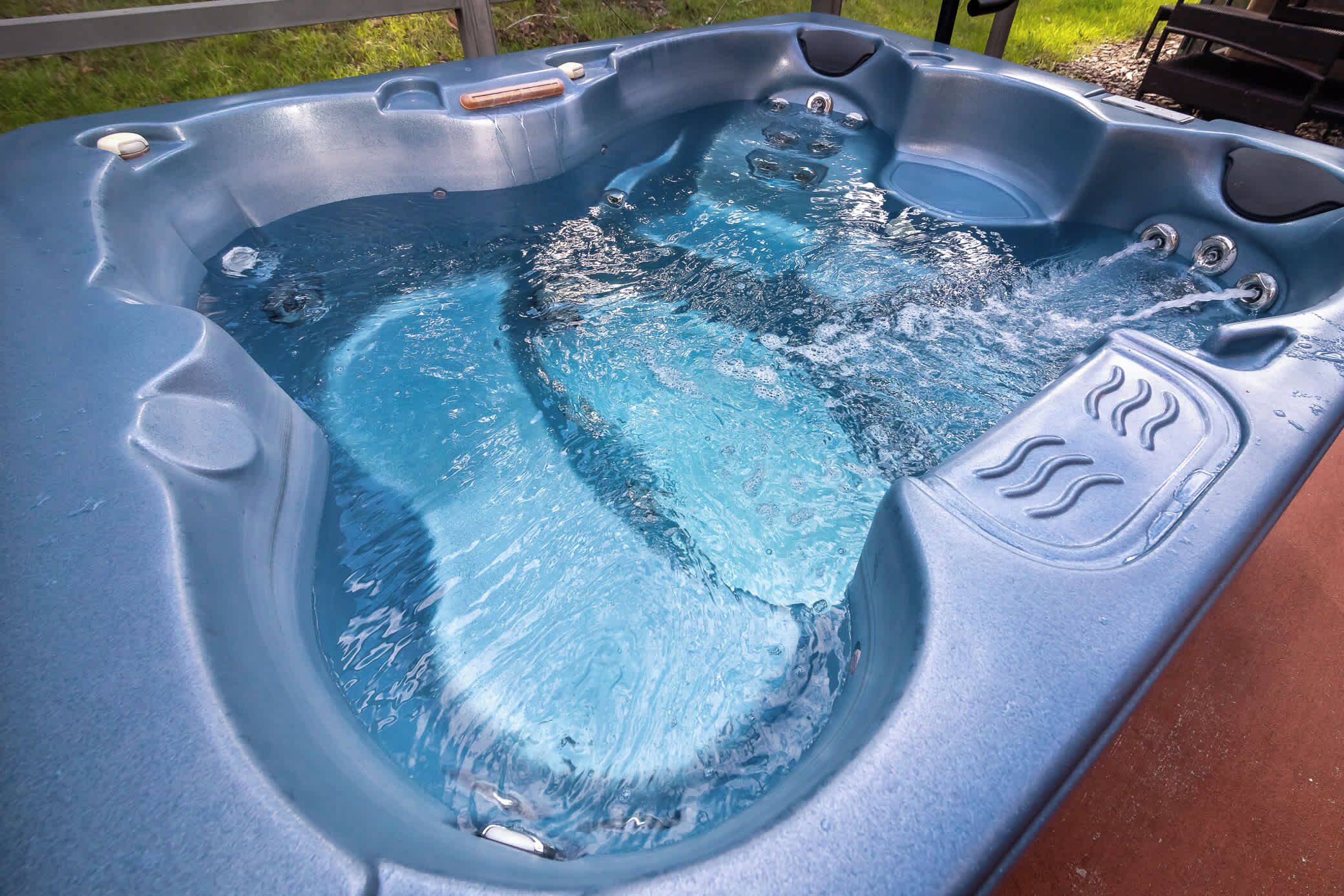 Una bañera de hidromasaje con asiento de madera y múltiples chorros.