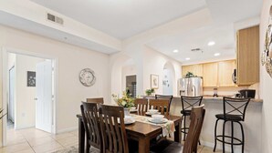 Un comedor con mesa y sillas de madera, una cocina con armarios de madera, y un reloj en la pared.