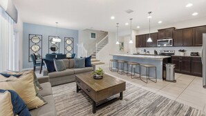 A modern kitchen with dark cabinets, a stainless steel refrigerator, and a central island with bar stools. - Windsor Grand Retreat - 11ppl! (Kissimmee)