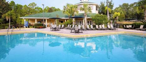 A pool with lounge chairs and a building with a green roof in the background.