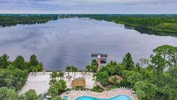 A resort with a large swimming pool, a beach area, and a view of a lake.