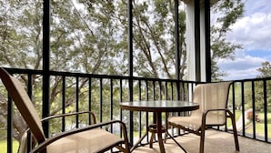 A balcony with two chairs and a table, overlooking a garden with trees. - Mickey's Terrace at the Bahama Bay Resort (Davenport)
