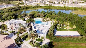 Luchtbeeld van een resort met een groot zwembad, palmbomen en een meer.