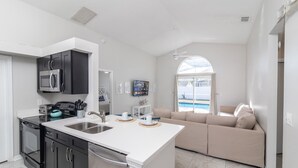 Una cocina moderna con una isla central, armarios negros y electrodomésticos de acero inoxidable.