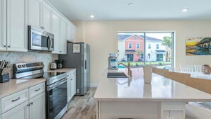 A modern kitchen with white cabinetry, stainless steel appliances, and a large island. - Turquoise Breeze - Close to Disney (Kissimmee)