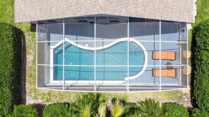 An aerial view of a modern house with a swimming pool, two sun loungers, and a well-maintained garden. - Beachy Retreat (Kissimmee)
