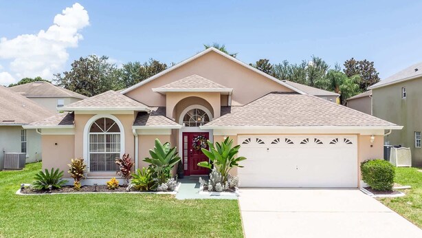 A single-story house with a red door, a garage, and a well-maintained lawn. - Beachy Retreat (Kissimmee)