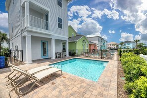A residential area with a swimming pool, a covered patio, and a two-story house with a balcony.