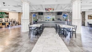Un vaste espace dédié à la salle à manger, avec un bar central, des colonnes blanches et un sol en pierre.