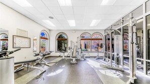 Une salle de sport équipée de divers appareils d’exercice, dotée de grandes fenêtres et présentant un design moderne et épuré.